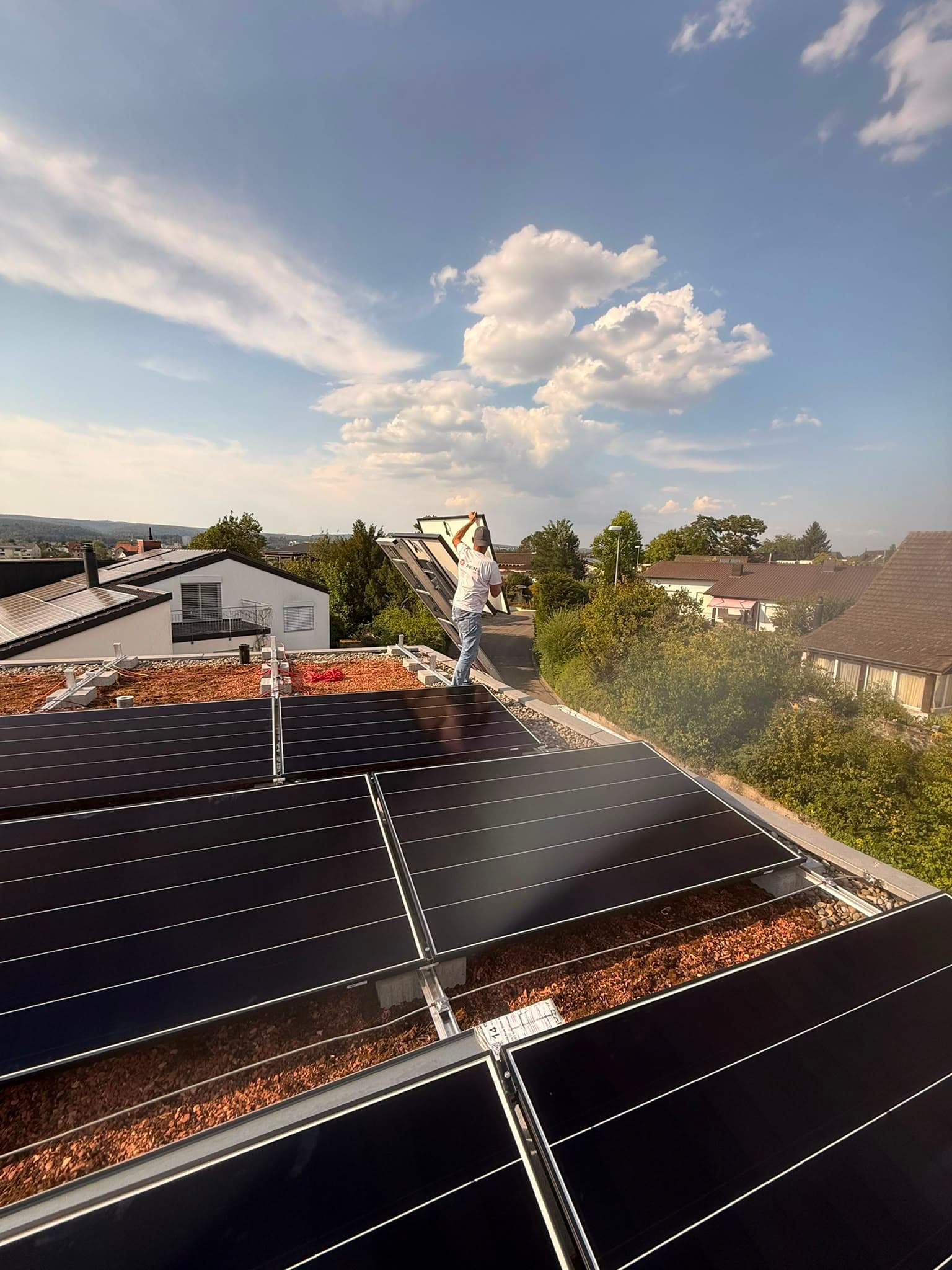 Monteur trägt ein Solarmodul über das Flachdach